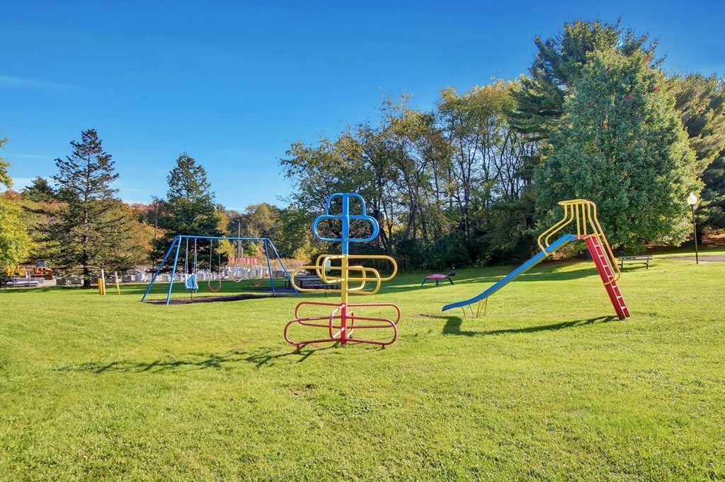 A playground with a blue slide, a red slide, and a yellow and red climbing frame.