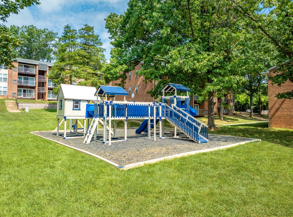 A playground with a blue slide and a white building in the background.