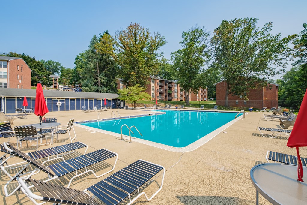 A sunny day at the pool with chairs and umbrellas.