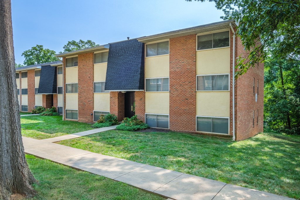 A row of apartment buildings with a sidewalk in front.