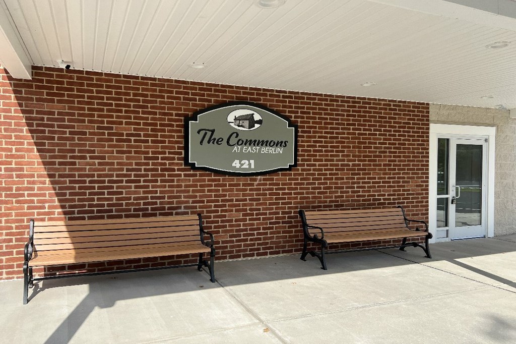 Two benches are placed in front of a sign that says The Commons.