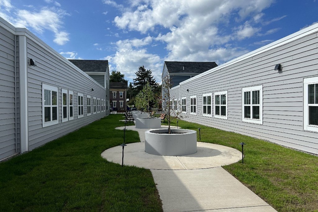 A courtyard with a circular planter in the middle of a concrete walkway.