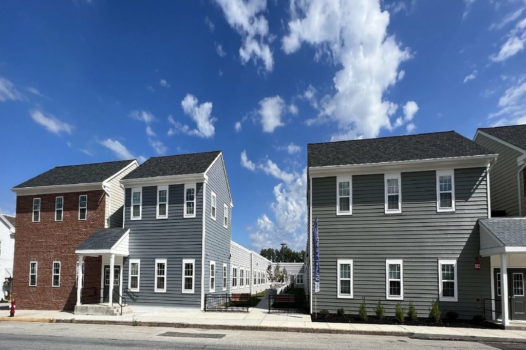 Two houses with grey and red brick facades stand side by side.