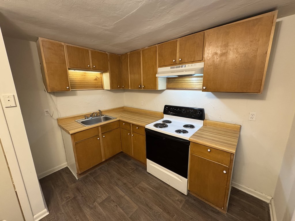 A small kitchen with wooden cabinets and a black stove top.