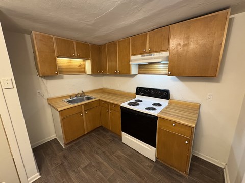 A small kitchen with wooden cabinets and a black stove top.