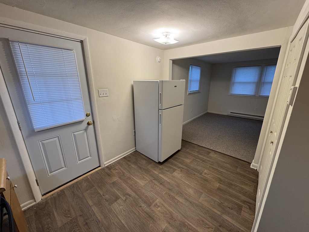 A kitchen with a white fridge and wooden floors.