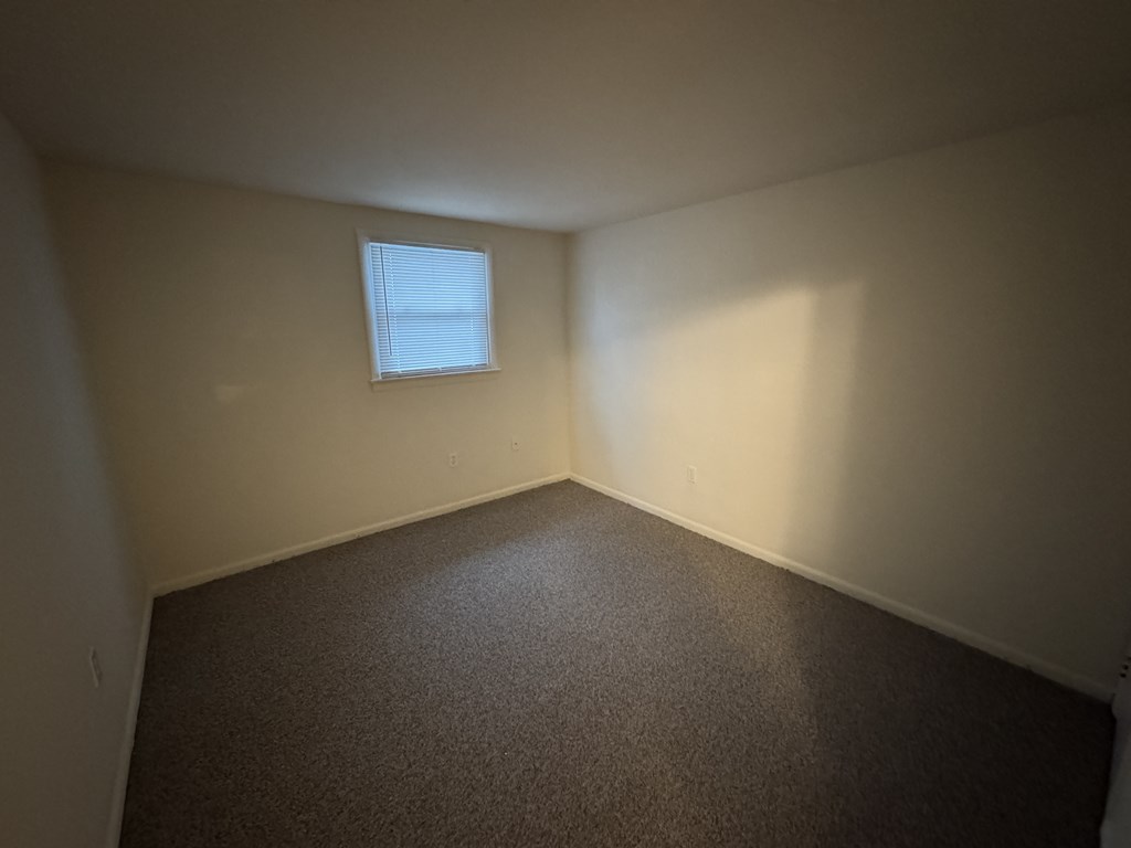 A room with a carpeted floor and a small window.