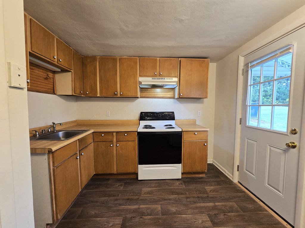 A kitchen with wooden cabinets and a black dishwasher.