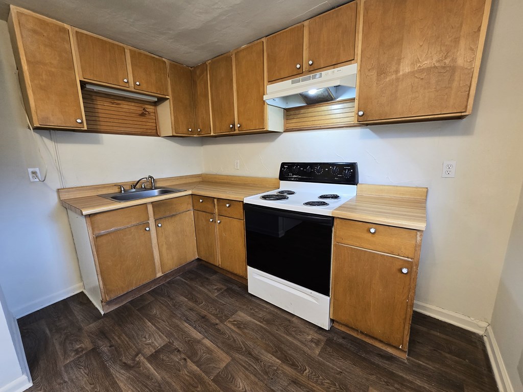 A kitchen with wooden cabinets and a black stove top oven.