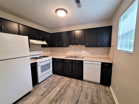 A kitchen with black cabinets and a white fridge.