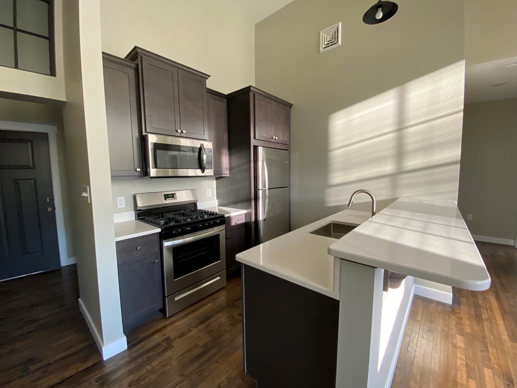 A kitchen with a white countertop and dark brown cabinets.