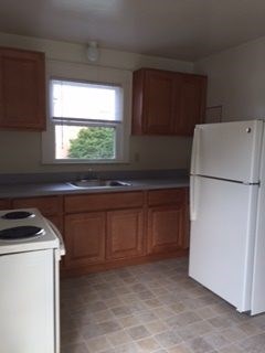 A white refrigerator is in a kitchen with brown cabinets.