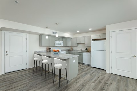 A kitchen with white cabinets and a marble island.