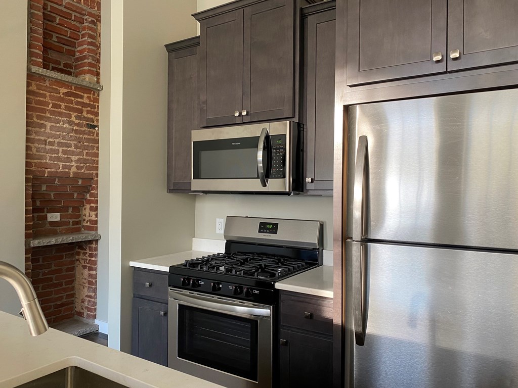 A kitchen with a stainless steel refrigerator, microwave, and oven.