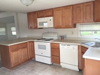 A kitchen with white appliances and wooden cabinets.