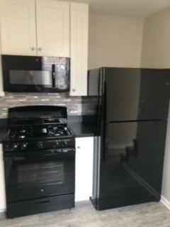 A black refrigerator stands in a kitchen next to a black stove.