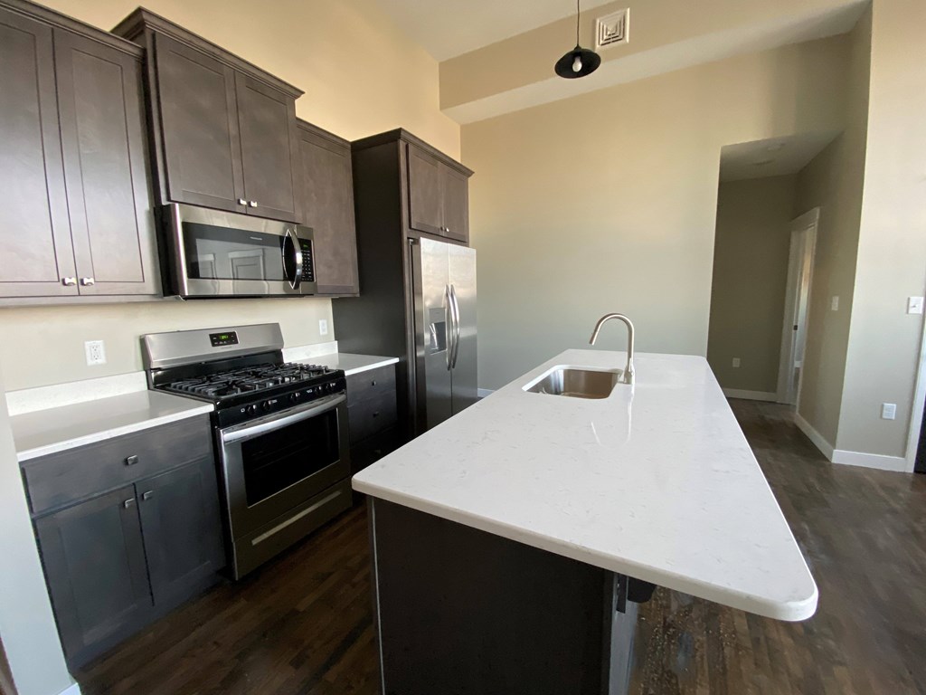 A kitchen with a white counter top and dark brown cabinets.