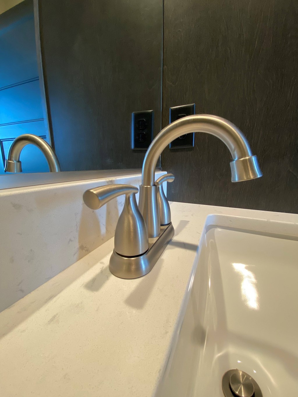 A chrome bathroom sink faucet with a white sink underneath.