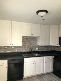 A kitchen with black countertops and white cabinets.