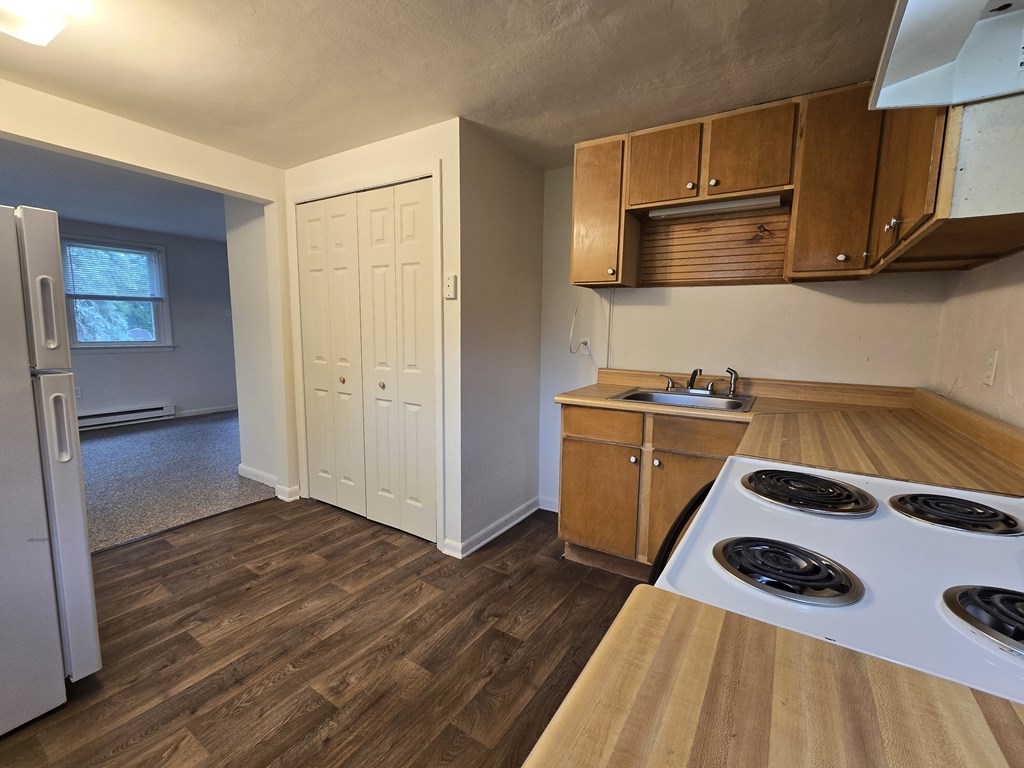 A kitchen with a white fridge, wooden cabinets, and a white door.