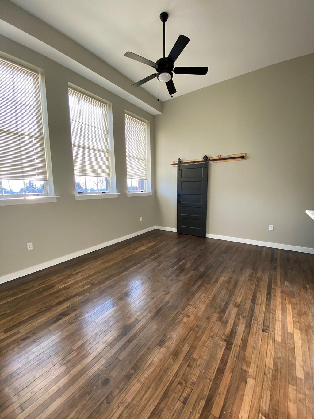 A room with a ceiling fan and wooden flooring.