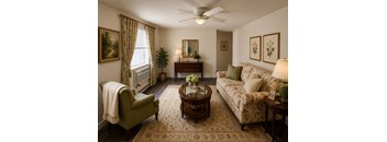 A living room with a green chair, a couch, a coffee table, and a ceiling fan.