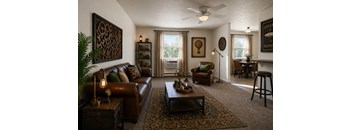 A living room with a brown leather couch and a coffee table with a lamp on it.