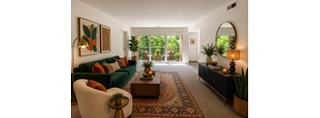 A living room with a green couch, a coffee table, and a mirror on the wall.