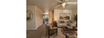 A living room with a white couch, a coffee table, and a ceiling fan.