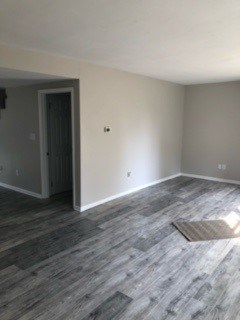 A room with a grey floor and a doorway leading to another room.