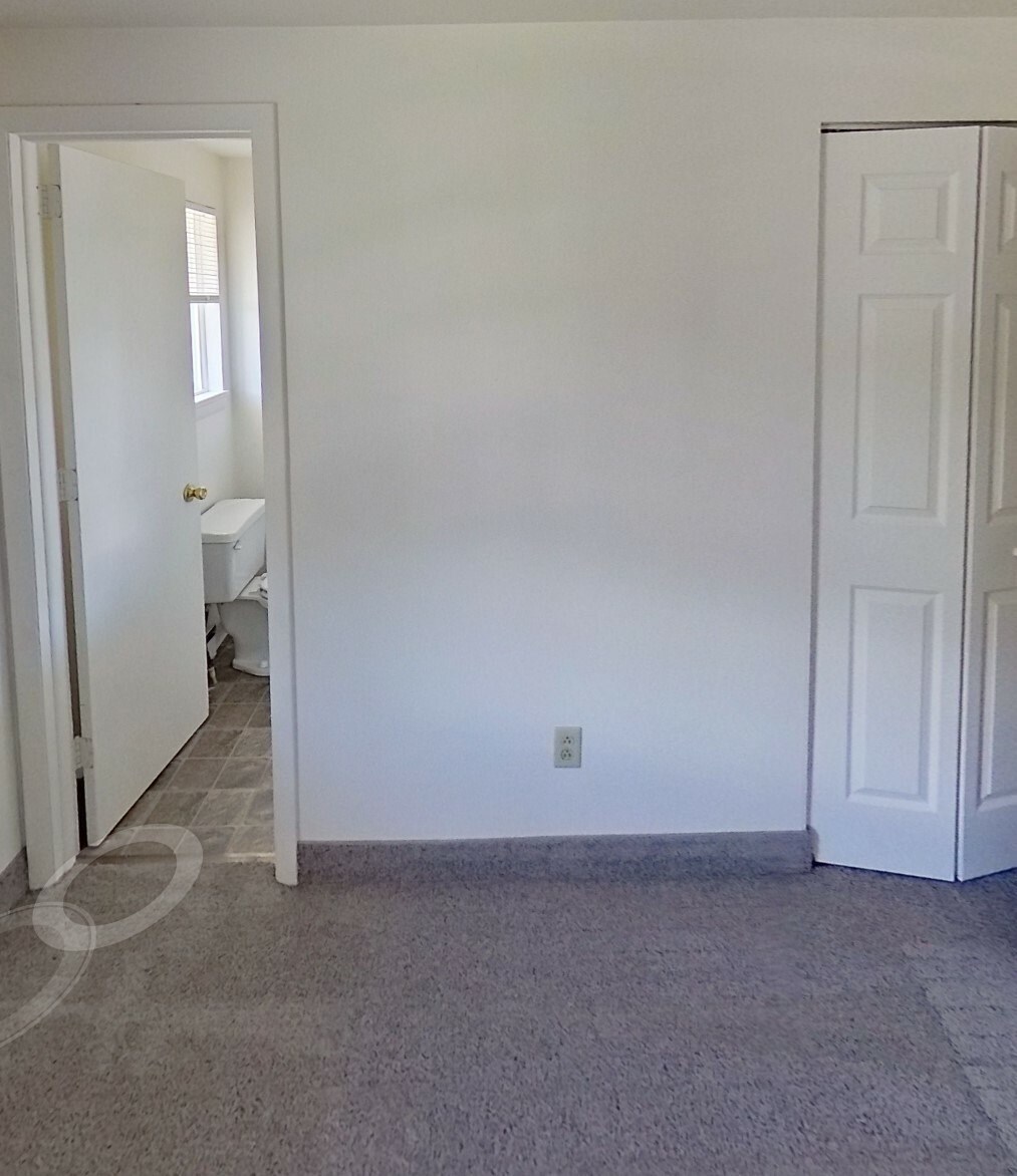 A white door is open to a small bathroom.