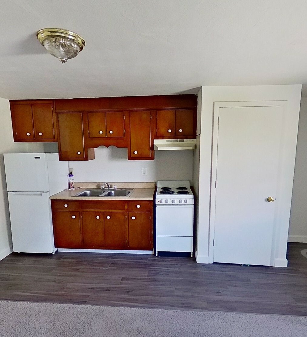 A kitchen with wooden cabinets and a white fridge.