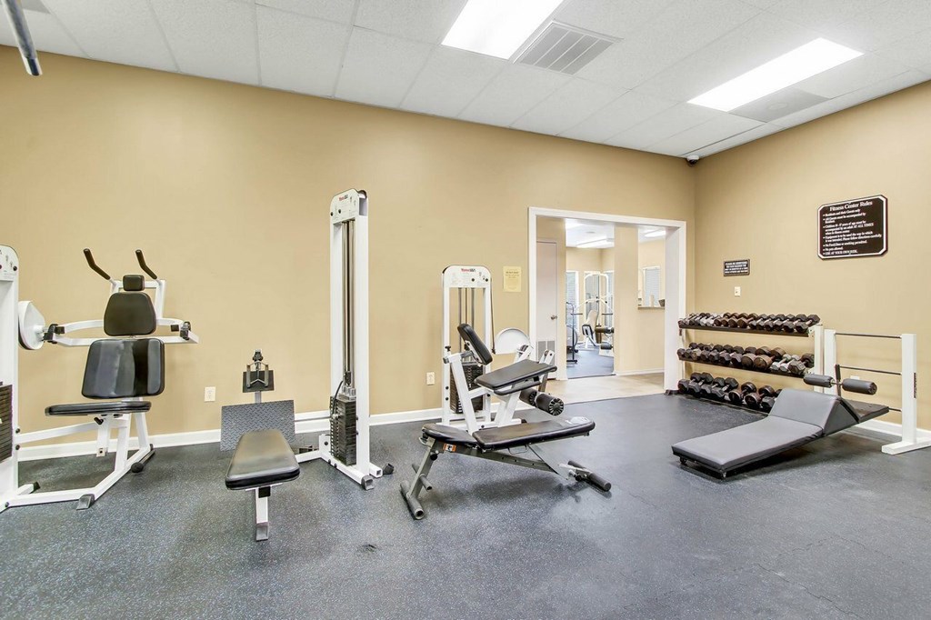 A gym with a variety of equipment including weights and weight machines.