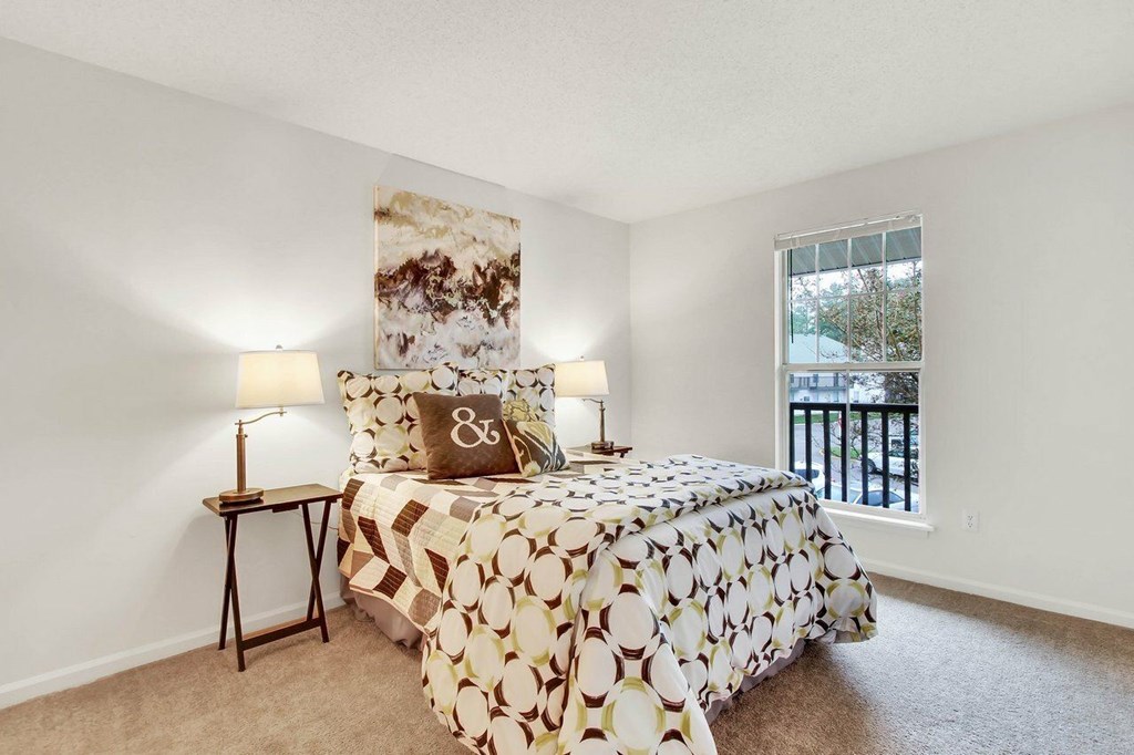 A bedroom with a bed, two lamps, and a painting on the wall.