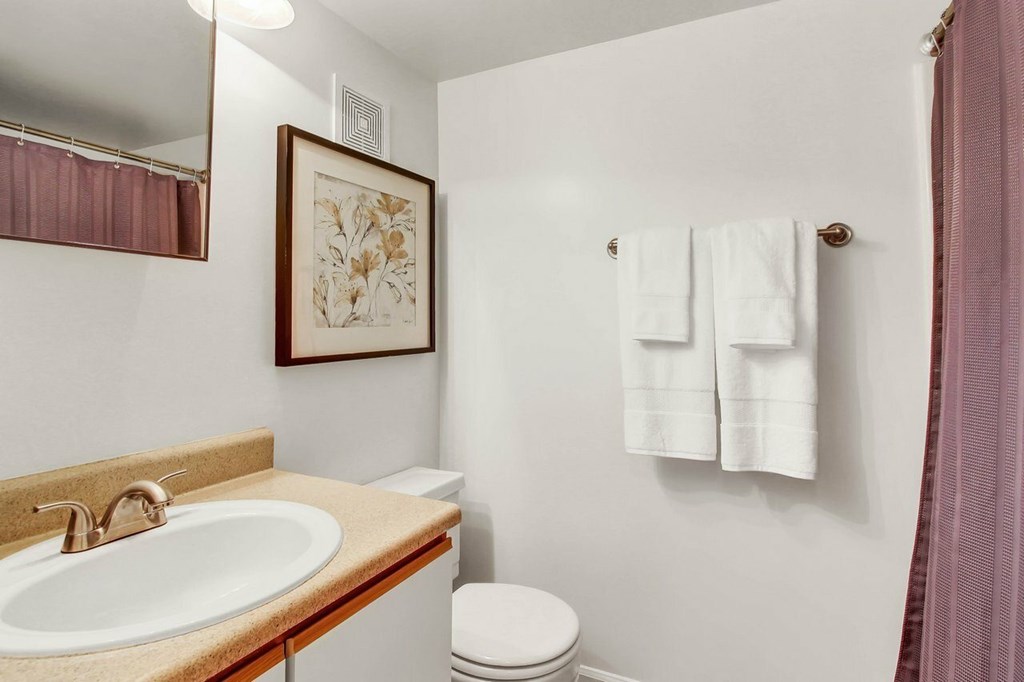 A bathroom with a toilet, sink, and towels.
