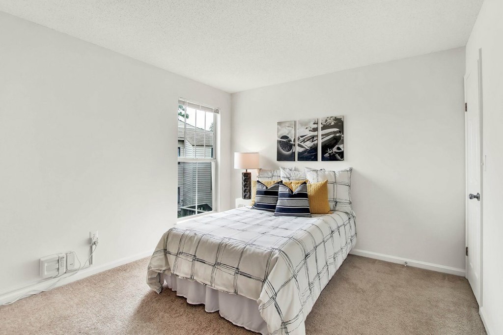 A bedroom with a bed, pillows, and a picture on the wall.