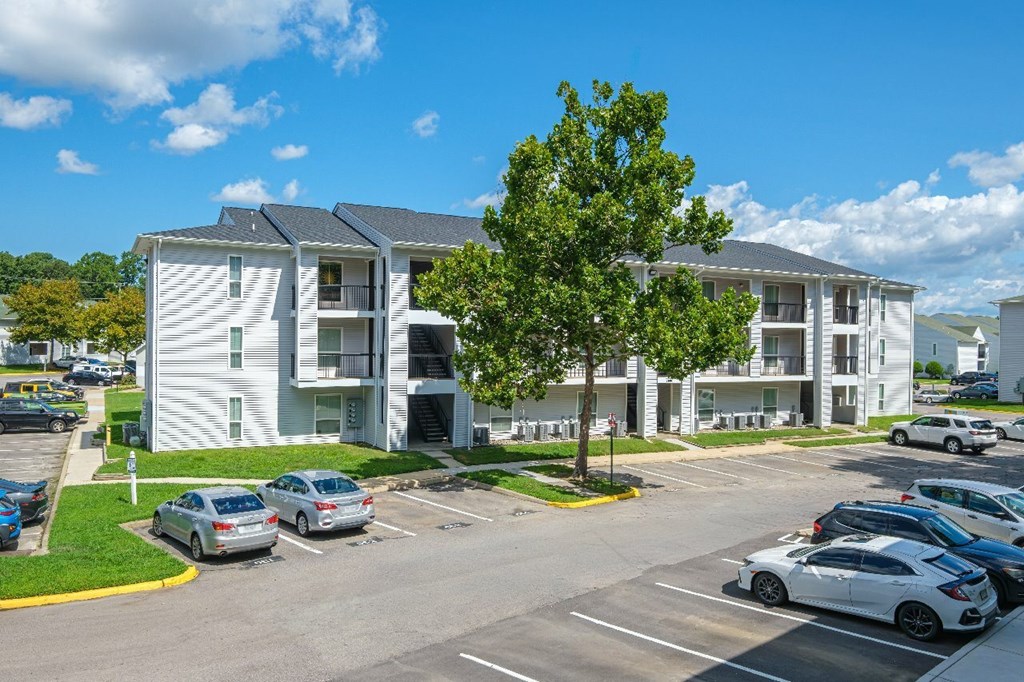 A white apartment building with a parking lot in front.