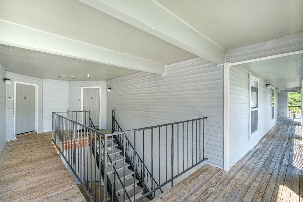 A white house with a black railing on the stairs.