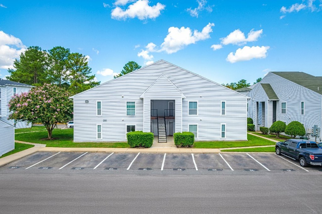 A white building with a parking lot in front.