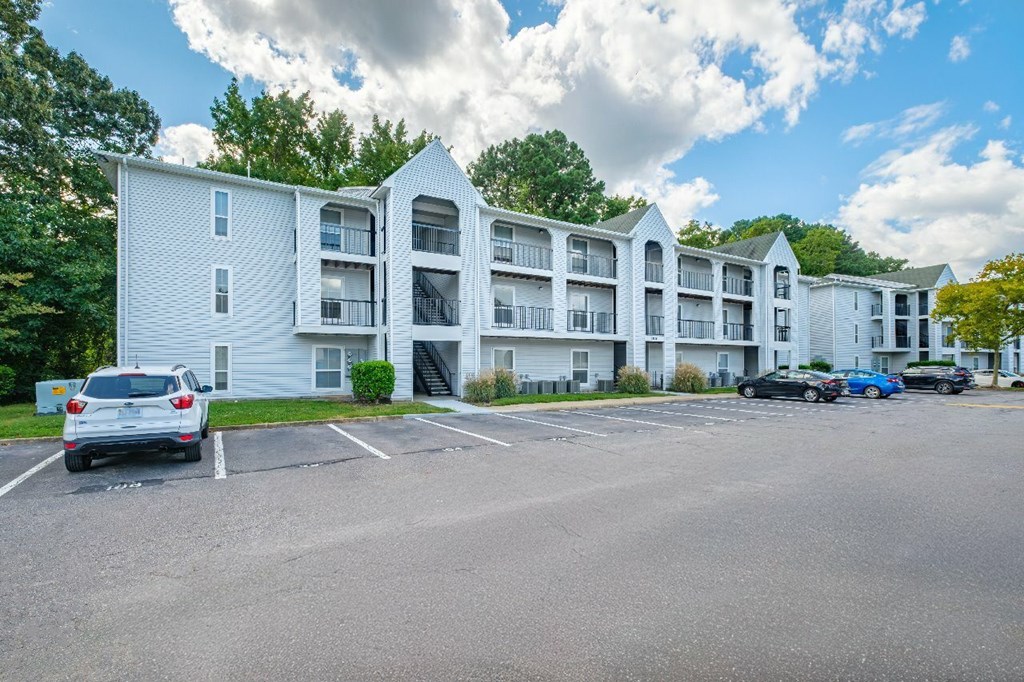 A white apartment building with a parking lot in front.