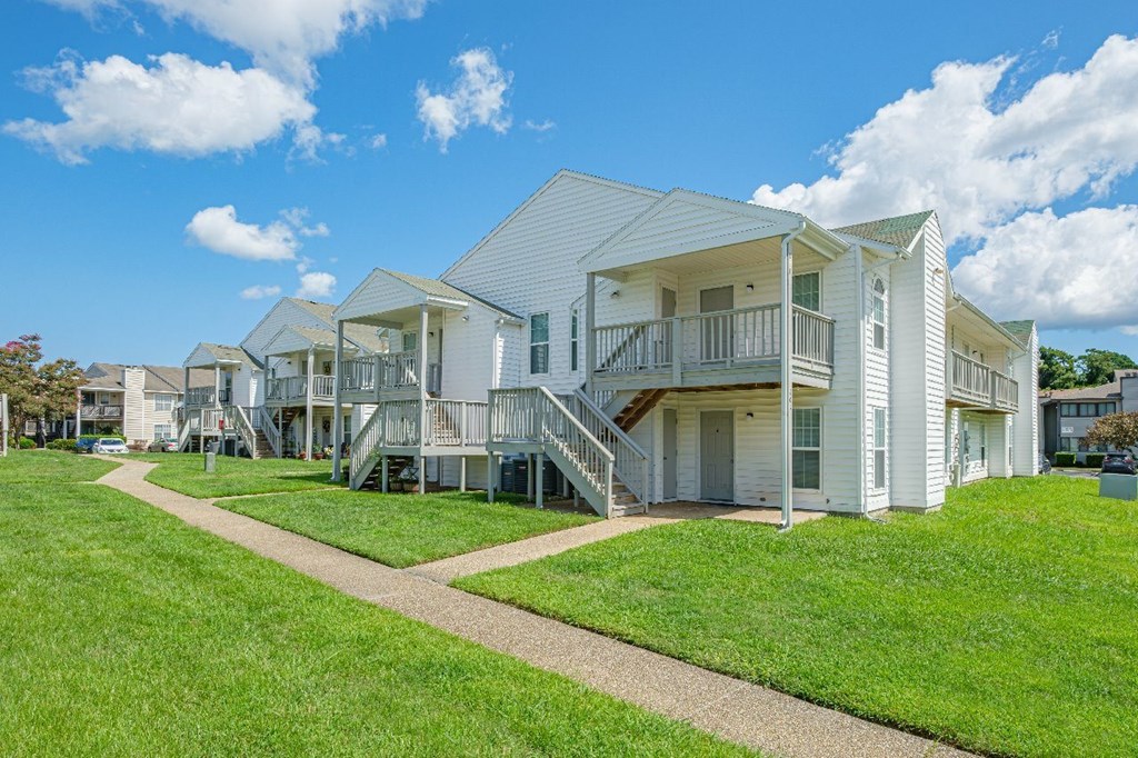 A row of white houses with green lawns in front.