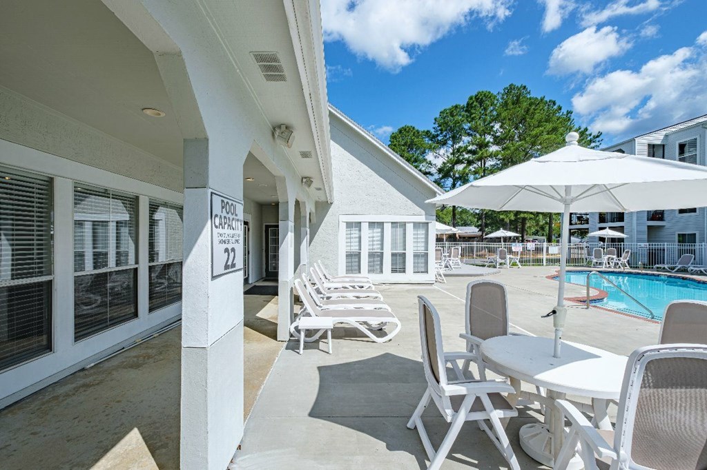 A poolside area with chairs and a pool umbrella.
