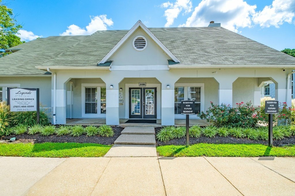 A white building with a green lawn in front.