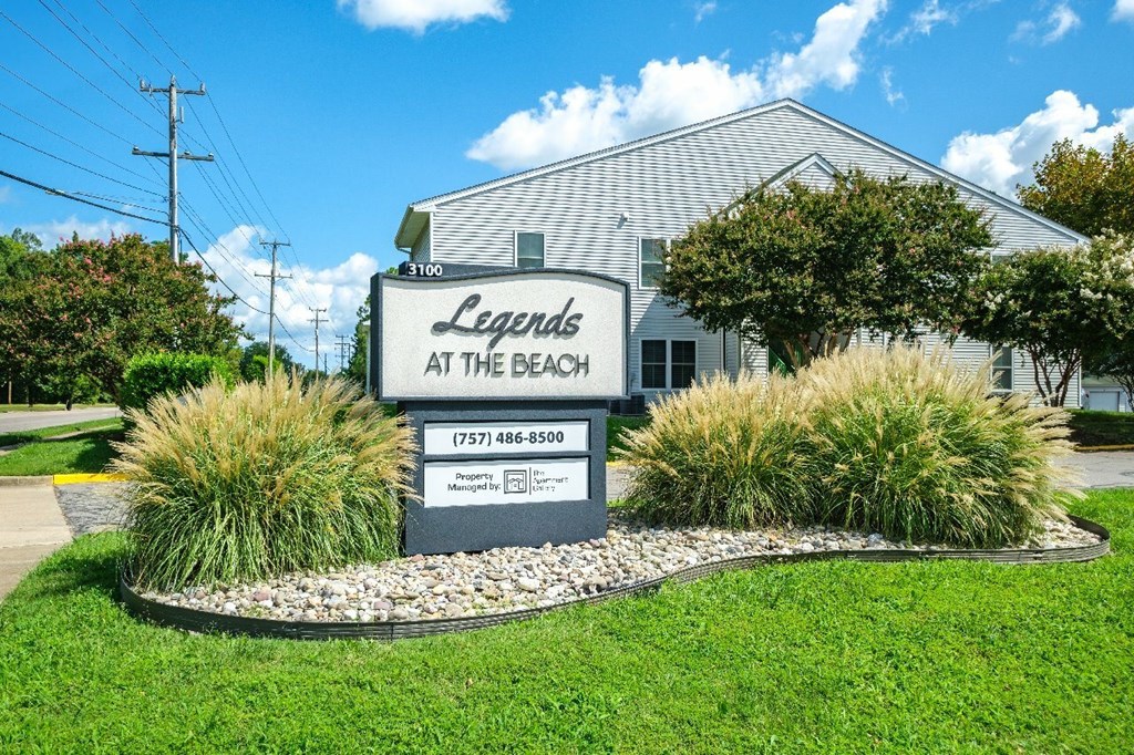 A sign for Legends at the Beach stands in front of a house.