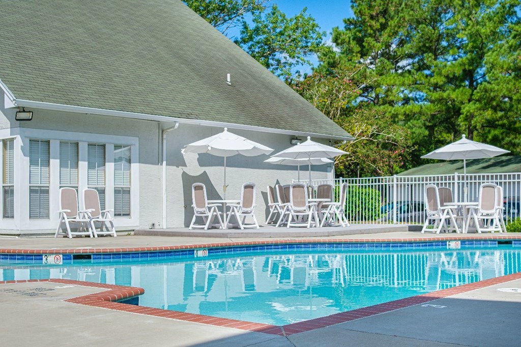 A pool with a red border and a white umbrella.