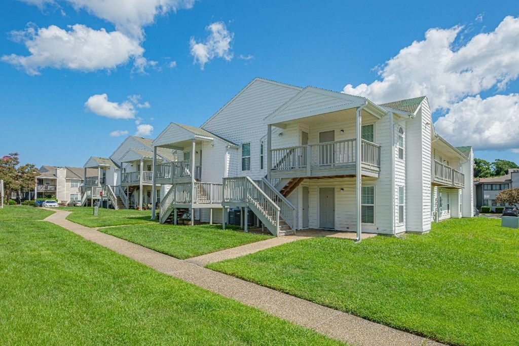 A row of white houses with green lawns in front.