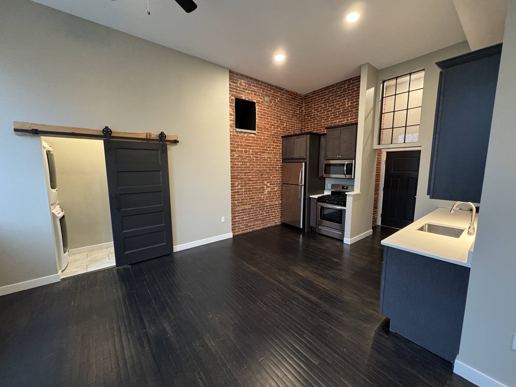 A kitchen with a brick wall and dark wood floors.