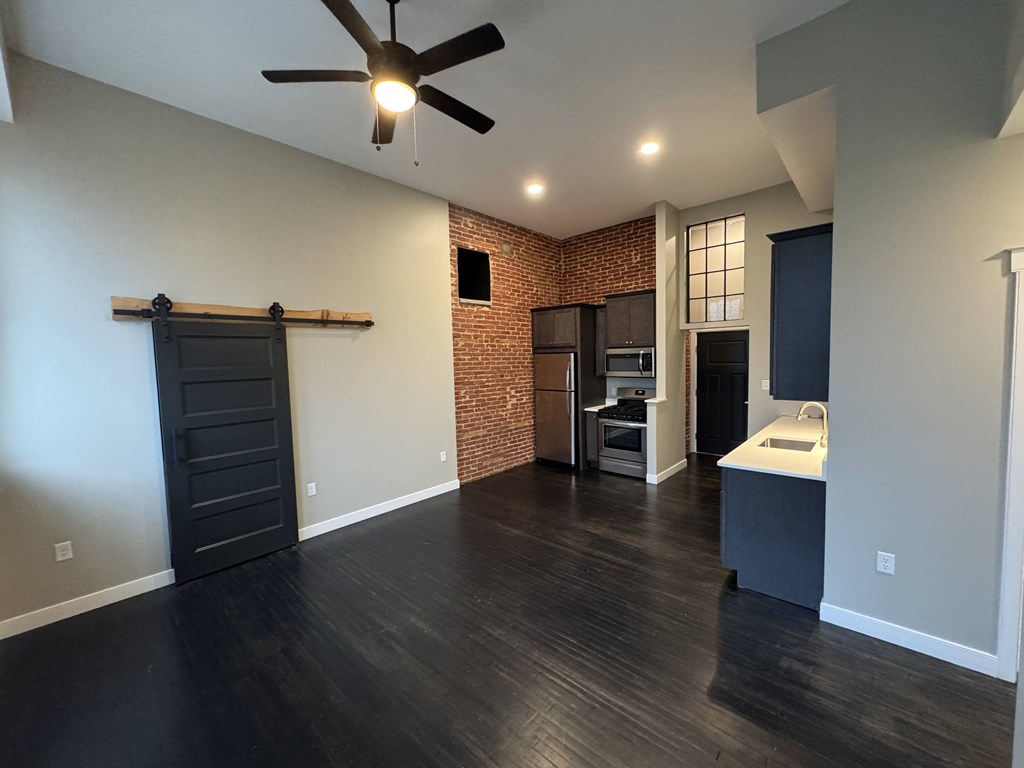 A room with a ceiling fan and a brick wall.