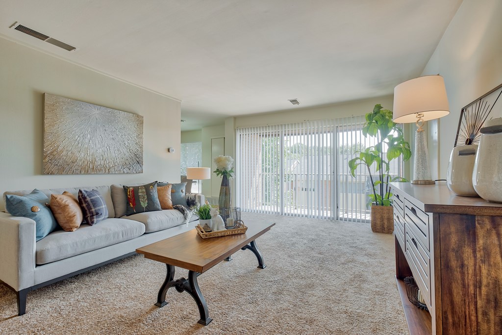 A living room with a grey couch, a wooden coffee table, and a painting on the wall.