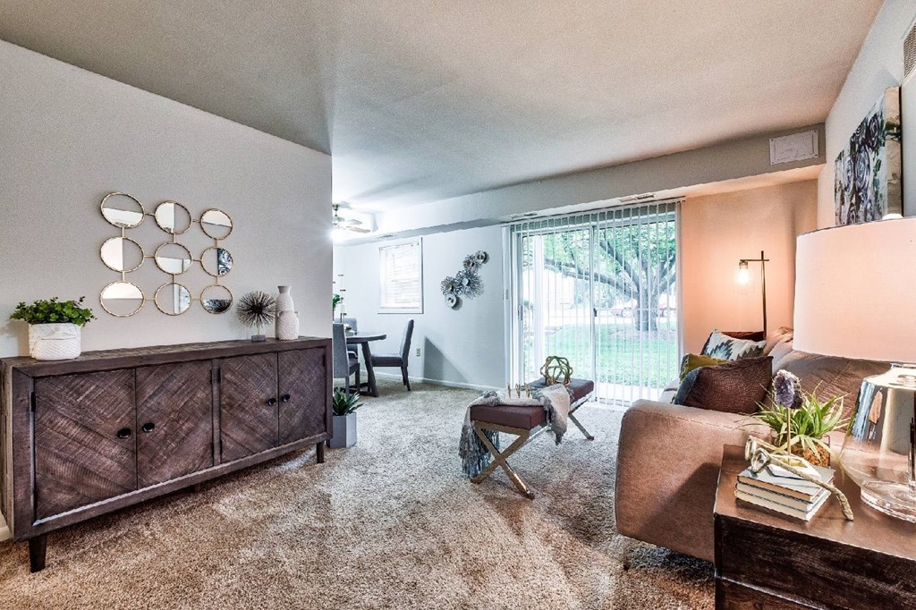 A living room with a brown sofa, a wooden cabinet, and a rug.